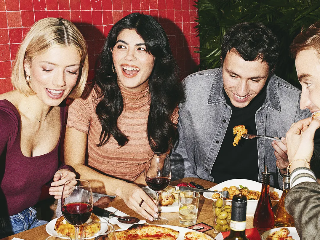 Friends sharing pizza, pasta and wine at Vapiano