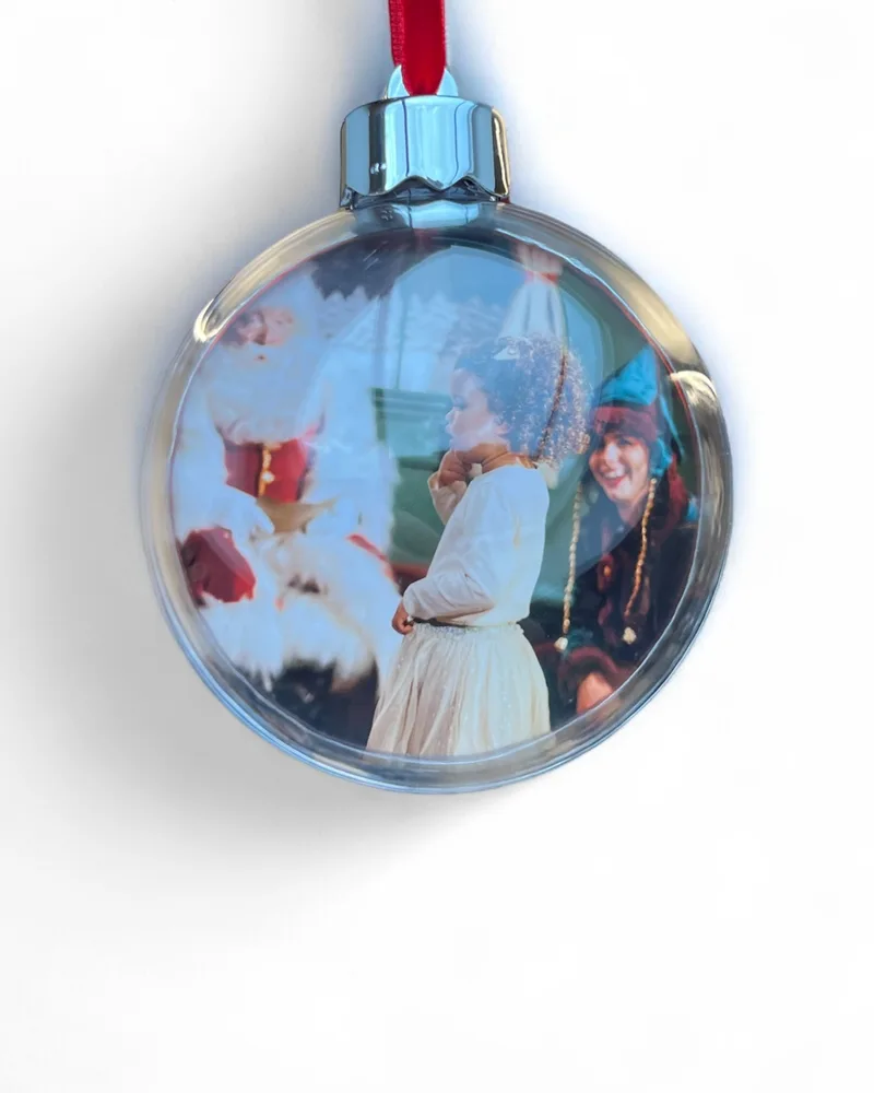 A red bauble on a ribbon with a family&rsquo;s photo with Santa inside it